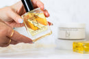 Elodie's Naturals: Hand holding golden body oil spray bottle