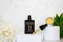 Elodie's Naturals: Dark serum bottle and open balm tin arranged with flowers